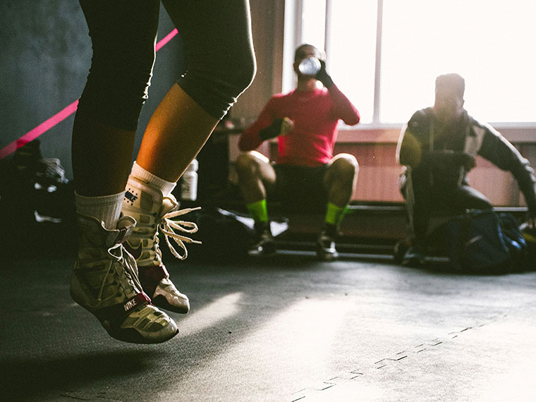Close up of someone's legs jumping off the ground, two people sat resting in the background