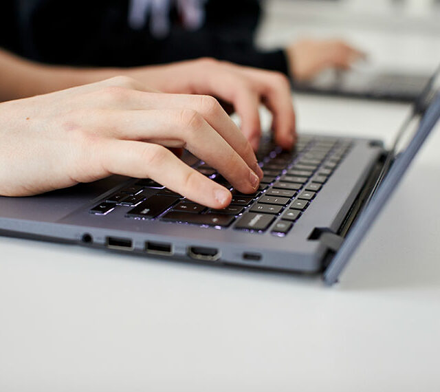 A close up of hands typing using a laptop